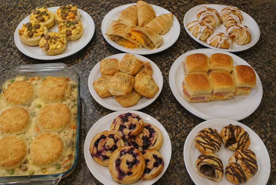 Homemade can biscuit recipes featuring breakfast cups, chicken casserole, sliders, biscuit pockets, and sweet pastries on serving plates.